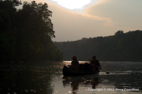 photograph of the silhouette of two men paddling a canoe on the Rappahannock River in Virginia