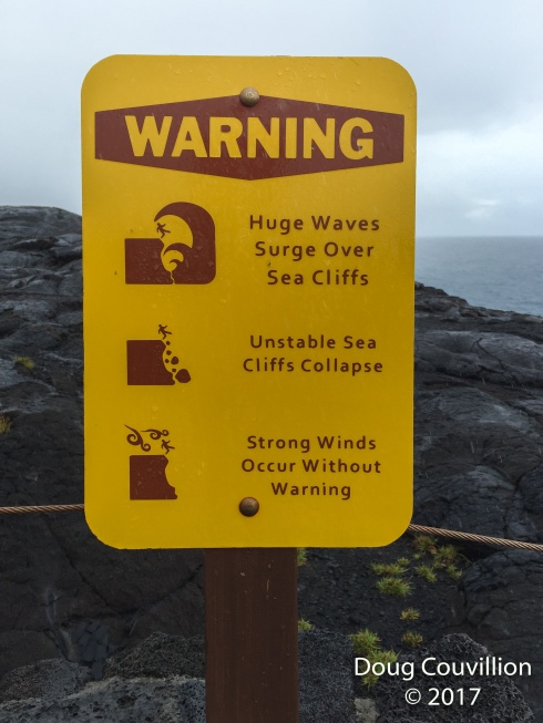 photo of a sign warning of huge wave, unstable cliffs and strong winds